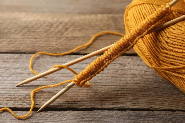 stock image Soft orange yarn, knitting and needles on wooden table, closeup