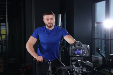 Man recording workout on camera at gym. Online fitness trainer