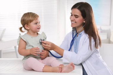 Klinikte steteskopla bebeği muayene eden çocuk doktoru.
