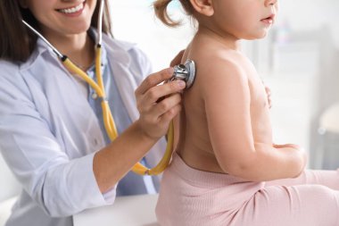 Klinikte steteskopla bebeği muayene eden çocuk doktoru.