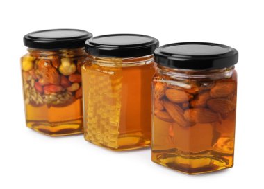 Farklı fındıklı kavanozlar ve beyaz arka planda bal