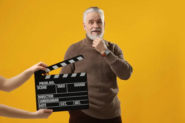 Hauptdarsteller Während Die Zweite Assistenzkamera Klappbrett Auf Gelbem Hintergrund Hält — Stockfoto