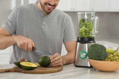 Lezzetli smoothie için avokado kesen adam mutfaktaki beyaz mermer masada, yakın plan.