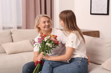 Küçük kızı evde çiçeklerle annesini tebrik ediyor. Anneler Günün kutlu olsun.