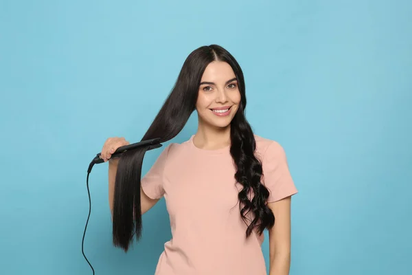 Schöne Glückliche Frau Mit Haarbügeleisen Auf Hellblauem Hintergrund — Stockfoto