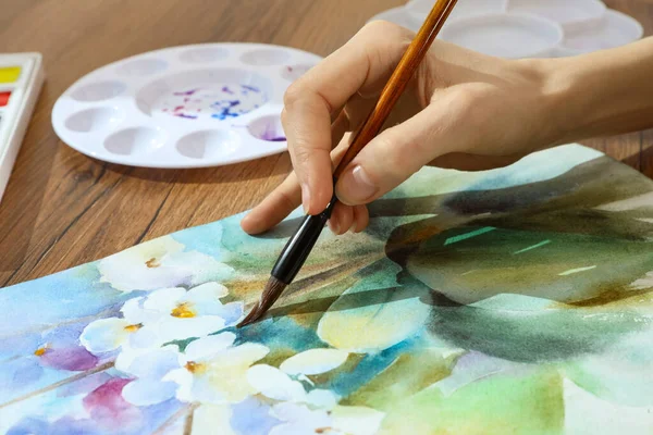 Stock image Woman painting flowers with watercolor at wooden table, closeup. Creative artwork