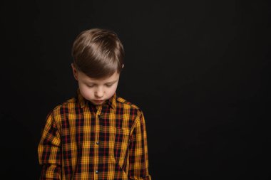 Siyah arka planda üzgün bir çocuk, mesaj için yer var. Çocukların zorbalığı.