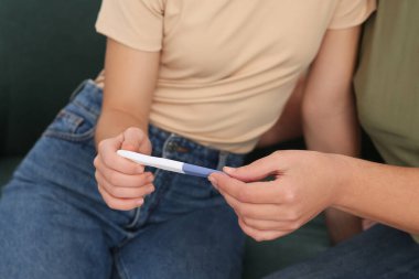 Annesinin hamilelik testini gösteren genç bir kadın, yakın plan. Müstakbel toruna büyük baba tepkisi