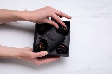 Beyaz mermer masanın üzerinde bir kutu lezzetli çikolata tutan kadın.