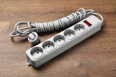 Tahta zeminde uzatma kablosu olan güç şeridi. Elektrikçi ekipmanı.