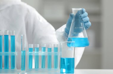 Laboratuvarda numuneyle birlikte matarayı tutan bilim adamı, yakın plan.