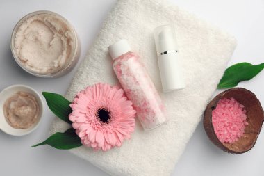 Farklı spa ürünleri ve beyaz masa üzerinde güzel bir çiçek içeren düz bir kompozisyon.