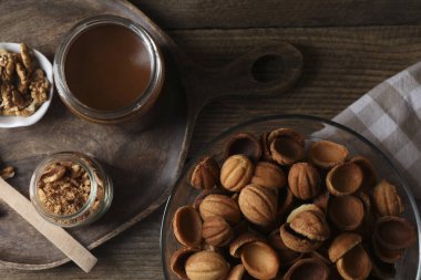 Ceviz şeklinde kurabiye yapıyorum. Pişmiş hamur, karamelize edilmiş konsantre süt ve ahşap masada fındık.