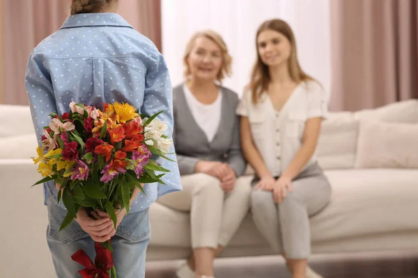 Stock image Little girl congratulating her mom and granny with flowers at home. Happy Mother's Day