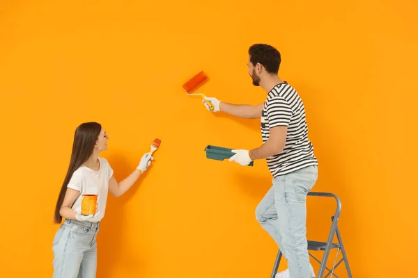 Σχεδιαστές Ζωγραφική Πορτοκαλί Τοίχο Ρολό Και Πινέλο — Φωτογραφία Αρχείου