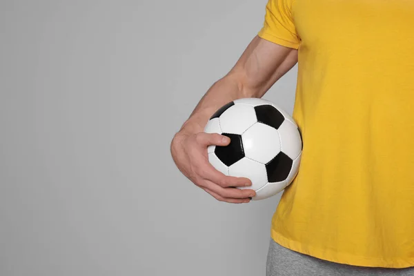 ライトグレーの背景にサッカーボールを持つアスレチックマン クローズアップ テキストのスペース — ストック写真