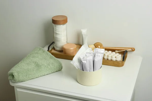 Different feminine and personal care products on white nightstand near white wall