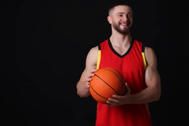 Siyah arka planda basketbol topu olan atletik bir genç. Metin için boşluk