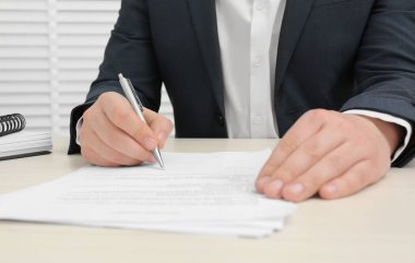 Ahşap masada belge imzalayan adam, yakın plan