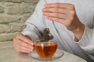 Kadın çay poşetini dışarı çıkarıyor. Kapalı bir masada, yakın plan.