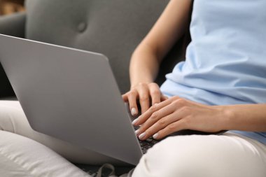 Kanepede dizüstü bilgisayarla çalışan bir kadın, yakın plan.