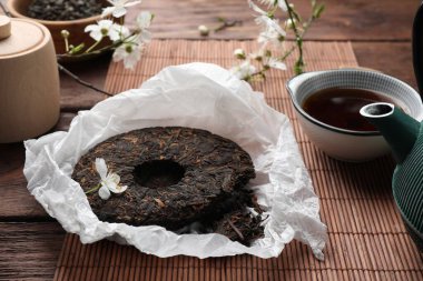Kırık disk şeklinde pu-erh çay ve bardakla ahşap masada içki.