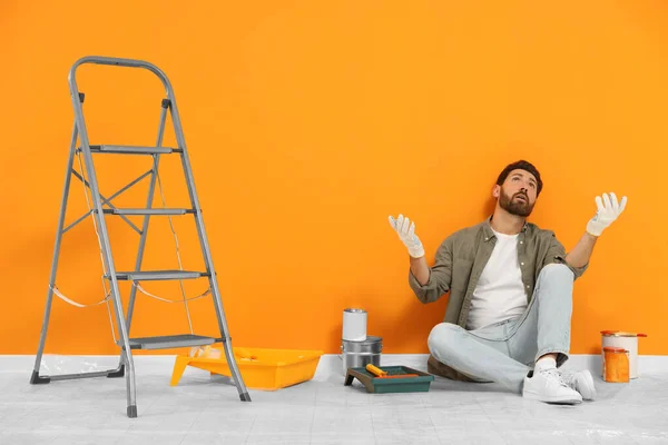 Συναισθηματικός Σχεδιαστής Που Κάθεται Στο Πάτωμα Κοντά Φρεσκοβαμμένο Πορτοκαλί Τοίχο — Φωτογραφία Αρχείου