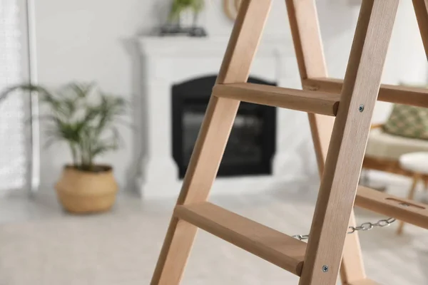 Wooden folding ladder in stylish living room, closeup. Space for text