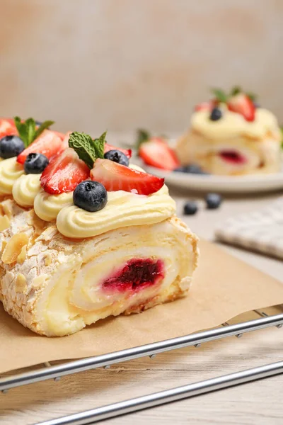 Tasty meringue roll with jam, cream, strawberry, blueberry and mint on white wooden table, closeup