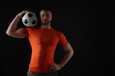 Siyah arka planda futbol topu olan atletik bir genç. Metin için boşluk