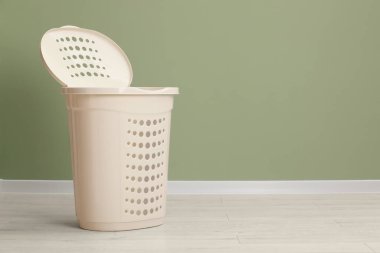 Empty plastic laundry basket near light green wall. Space for text