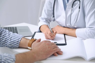 Beyaz masadaki doktora danışmanlık yapan hasta, yakın plan.