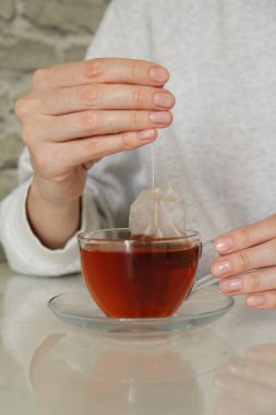 Kadın çay poşetini dışarı çıkarıyor. Kapalı bir masada, yakın plan.