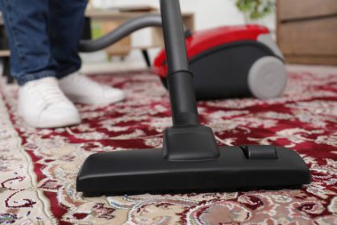 Halıyı elektrikli süpürgeyle temizleyen adam, yakın plan.