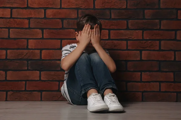 Αναστατωμένο Αγόρι Που Κάθεται Στο Πάτωμα Κοντά Τοίχο Από Τούβλα — Φωτογραφία Αρχείου