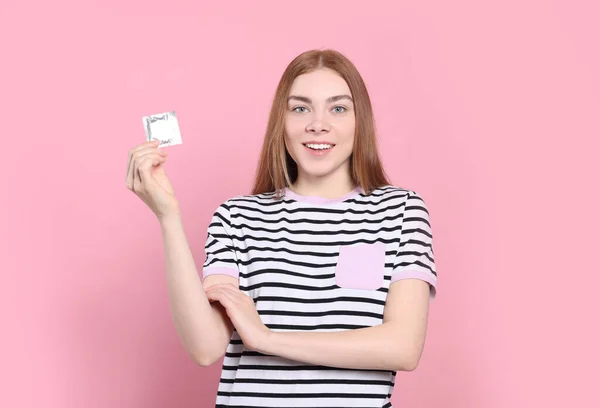 ピンクを背景にコンドームを持つ女性 安全なセックス — ストック写真