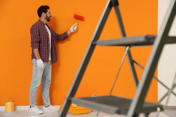 Designer Painting Orange Wall Roller Folding Ladder Indoors — Φωτογραφία Αρχείου
