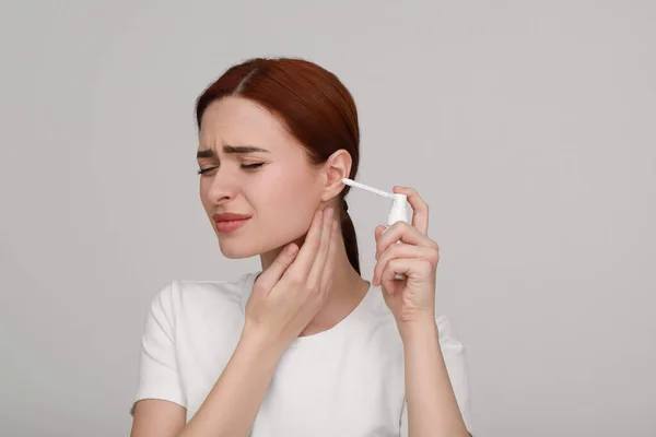 Mutsuz Kadın Açık Gri Arka Planda Kulak Spreyi Kullanıyor — Stok fotoğraf