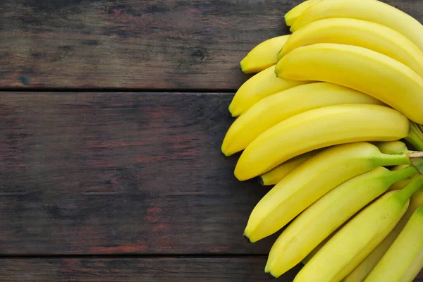 stock image Ripe yellow bananas on wooden table, flat lay. Space for text