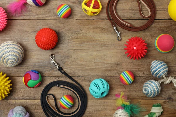 Flat lay composition with pet leashes and toys on wooden background, space for text