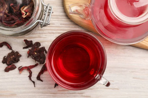 stock image Delicious hibiscus tea and dry flowers on white wooden table, flat lay