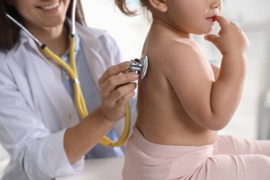 Klinikte steteskopla bebeği muayene eden çocuk doktoru.