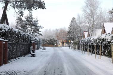 Beautiful view of city street with cottages and trees on winter day