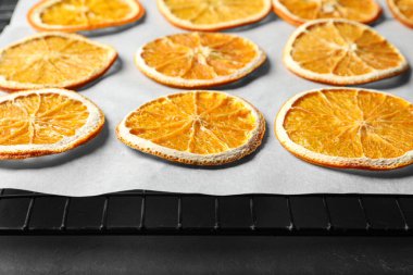 Dry orange slices on parchment paper, closeup