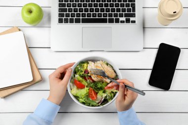 Ofis çalışanı iş yerinde öğle yemeği yiyor.