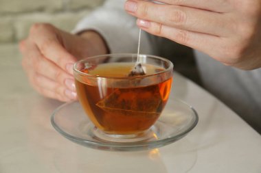 Kadın çay poşetini dışarı çıkarıyor. Kapalı bir masada, yakın plan.
