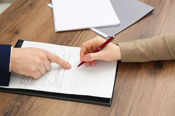 Mann Zeigt Auf Dokument Und Frau Legt Unterschrift Auf Holztisch — Stockfoto