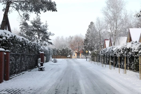 Beautiful view of city street with cottages and trees on winter day