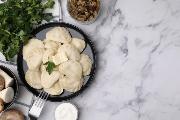 stock image Delicious dumplings (varenyky) with mushrooms, parsley, butter and sour cream served on white marble table, flat lay. Space for text