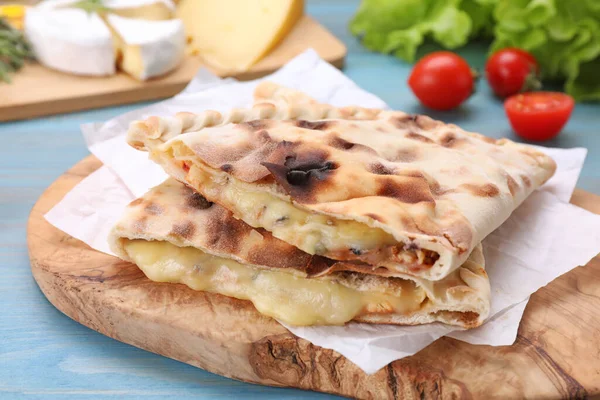 Açık mavi ahşap masada peynirli leziz pizza calzone 'leri.